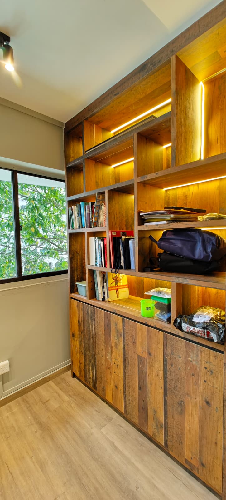 Study room with full-wall rustic timber bookshelf featuring LED-lit compartments